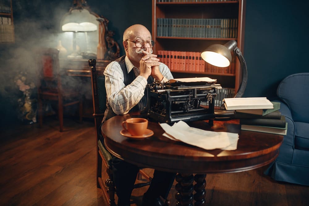 Elderly writer thinks at vintage typewriter